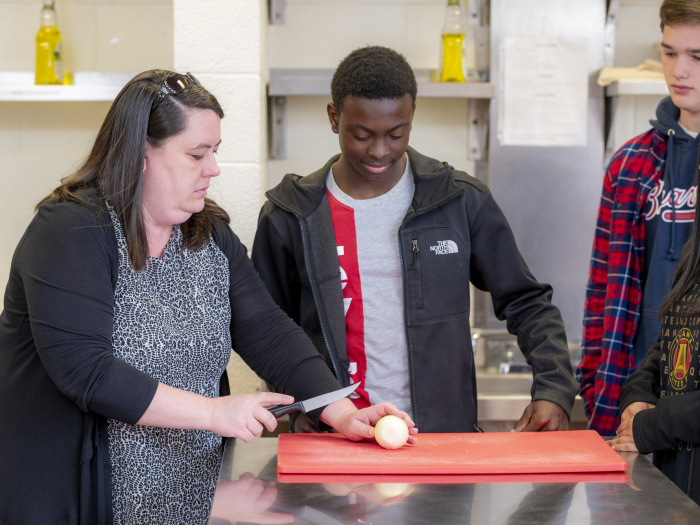 An instructor teaches students about a proper food handling method.