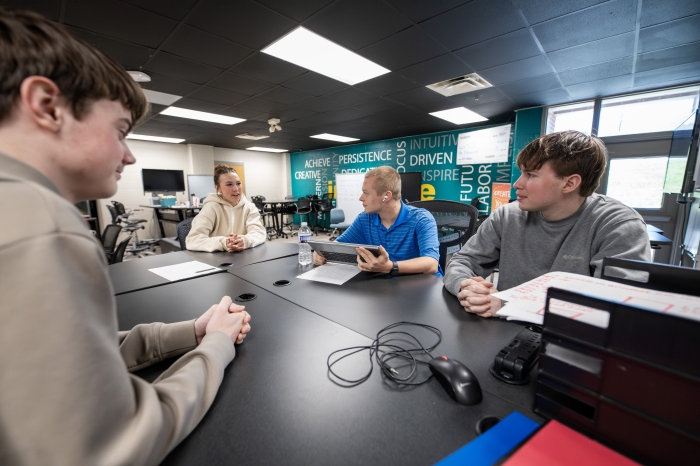 Students discuss around a table.