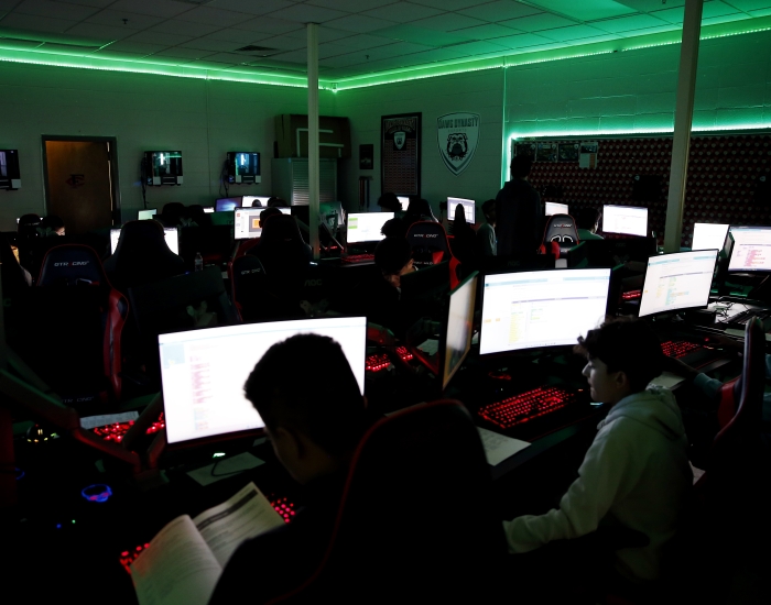 Students work in a computer lab lit by green light.
