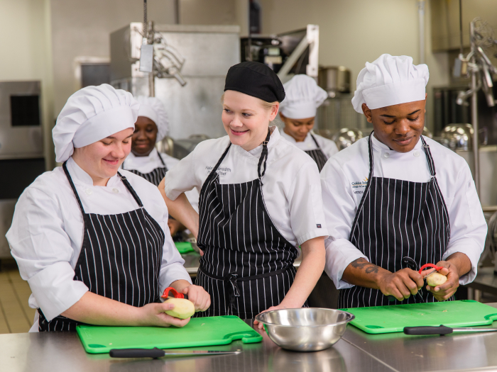 Students practice peeling potatoes with an instructor.