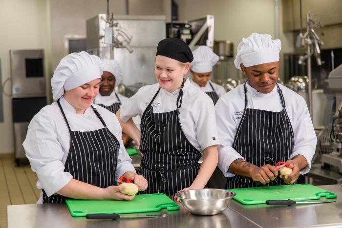 Students practice a culinary task with an instructor.